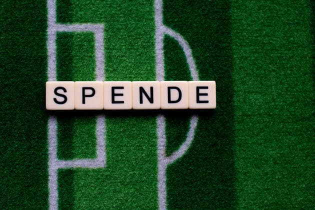 Das Coronavirus (Covid-19) verursacht Veranstaltungsabsagen von beispielsweise Fußballspielen der Bundesligaprofiligen auf unbestimmte Zeit und viele Auswirkungen, im Bild: Das Wort Spende auf einem Fußballteppich. Deutschland