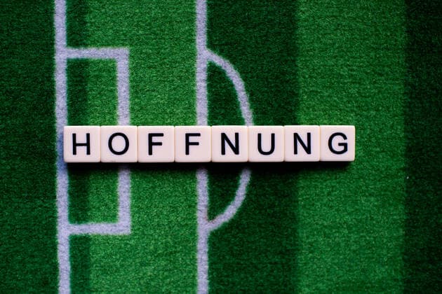 Das Coronavirus (Covid-19) verursacht Veranstaltungsabsagen von beispielsweise Fußballspielen der Bundesligaprofiligen auf unbestimmte Zeit und viele Auswirkungen, im Bild: Das Wort Hoffnung auf einem Fußballteppich. Deutschland
