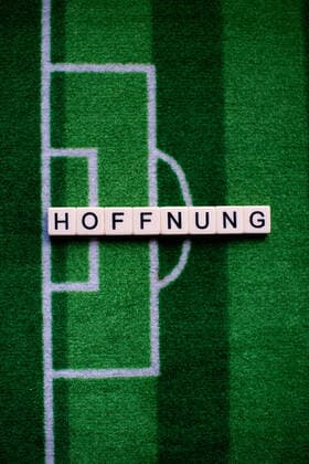 Das Coronavirus (Covid-19) verursacht Veranstaltungsabsagen von beispielsweise Fußballspielen der Bundesligaprofiligen auf unbestimmte Zeit und viele Auswirkungen, im Bild: Das Wort Hoffnung auf einem Fußballteppich. Deutschland