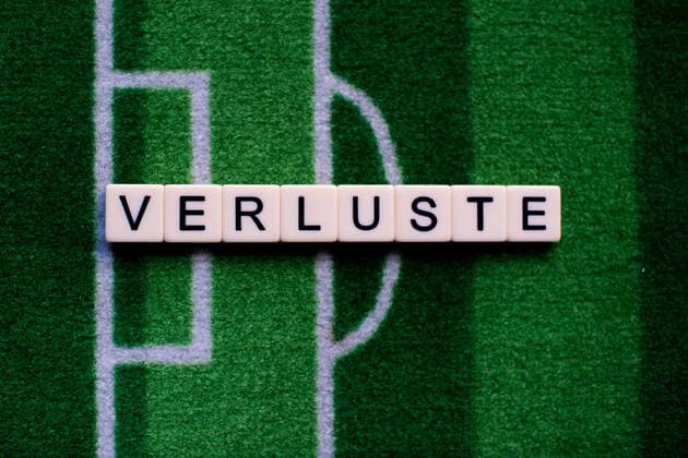 Das Coronavirus (Covid-19) verursacht Veranstaltungsabsagen von beispielsweise Fußballspielen der Bundesligaprofiligen auf unbestimmte Zeit und viele Auswirkungen, im Bild: Das Wort Verluste auf einem Fußballteppich. Deutschland