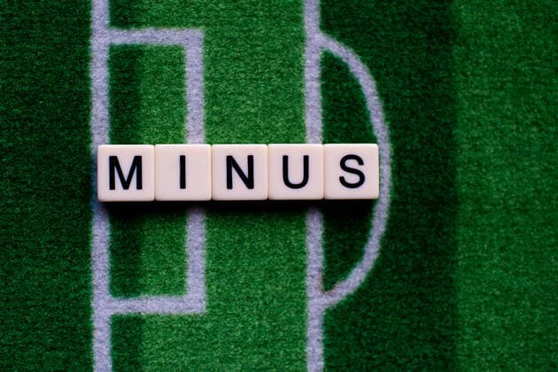Das Coronavirus (Covid-19) verursacht Veranstaltungsabsagen von beispielsweise Fußballspielen der Bundesligaprofiligen auf unbestimmte Zeit und viele Auswirkungen, im Bild: Das Wort Minus auf einem Fußballteppich. Deutschland