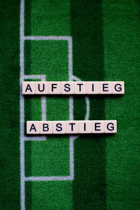 Das Coronavirus (Covid-19) verursacht Veranstaltungsabsagen von beispielsweise Fußballspielen der Bundesligaprofiligen auf unbestimmte Zeit und viele Auswirkungen, im Bild: Das Wort Aufstieg und Abstieg auf einem Fußballteppich. Deutschland