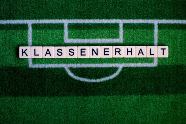 Das Coronavirus (Covid-19) verursacht Veranstaltungsabsagen von beispielsweise Fußballspielen der Bundesligaprofiligen auf unbestimmte Zeit und viele Auswirkungen, im Bild: Das Wort Klassenerhalt auf einem Fußballteppich. Deutschland