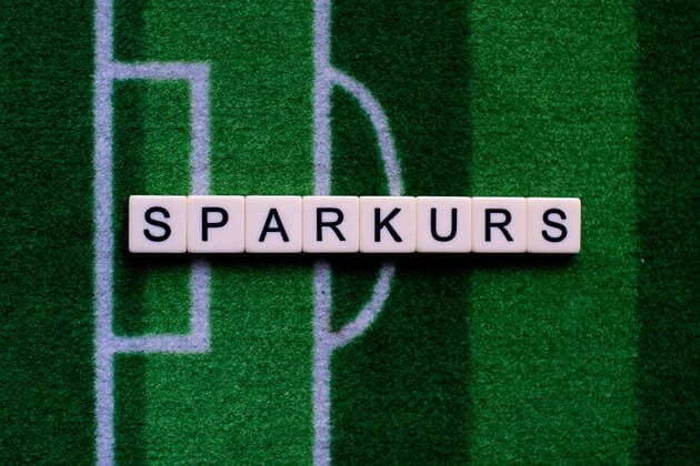 Das Coronavirus (Covid-19) verursacht Veranstaltungsabsagen von beispielsweise Fußballspielen der Bundesligaprofiligen auf unbestimmte Zeit und viele Auswirkungen, im Bild: Das Wort Sparkurs auf einem Fußballteppich. Deutschland