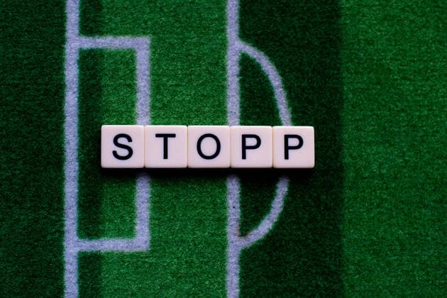 Das Coronavirus (Covid-19) verursacht Veranstaltungsabsagen von beispielsweise Fußballspielen der Bundesligaprofiligen auf unbestimmte Zeit und viele Auswirkungen, im Bild: Das Wort Stopp auf einem Fußballteppich. Deutschland