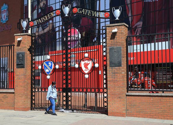 May 4th 2020, Liverpool, United Kingdom; Anfield stadium during the suspension of the Premier League due to the Covid-19 virus pandemic; a woman wearing a face mask walks past the locked Paisley Gateway entrance to the Kop  ActionPlus12218569 DavidxBlunsden