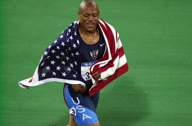 OLYMPICS RUNNING ATHLETICS, 23rd September, 2000. Sydney Olympic Games, Olympische Spiele, Olympia, OS Athletics, Mens 100M Final. Maurice Greene (USA) walks a victory lap draped in the American Flag after winning the Mens 100M Final. (Dean Lewins AAP Image) NO ARCHIVING, EDITORIAL USE ONLY, NO USE IN BOOKS WITHOUT CONSENT SYDNEY AUS  Copyright: xDEANxLEWINSx 0104102907st