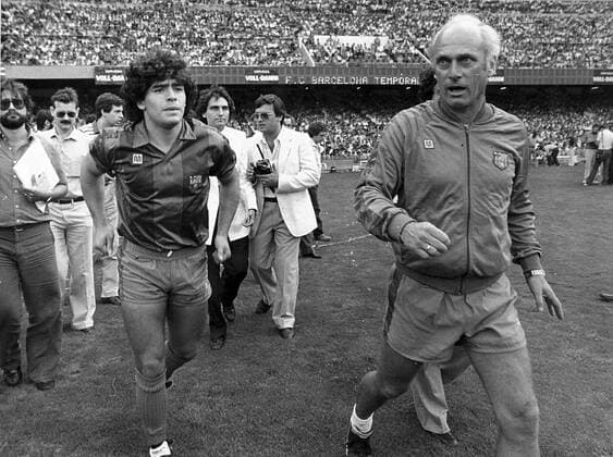 El entrenador del FC Barcelona, Barca (d) Udo Lattek saltando al campo junto a sus jugadores Diego Maradona, rodeados de fotografos y periodistas, en el acto de presentacion para la nueva temporada. 