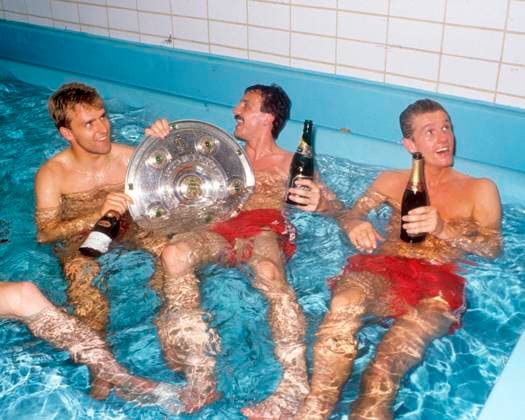 FC Bayern München Deutscher Meister 1990. Meisterfeier des FC Bayern in der Kabine. 12.05.1990. V.l: Hans-Dieter Hansi Flick, Jürgen Kohler und Thomas Strunz mit der Meisterschale im Entmüdungsbecken.