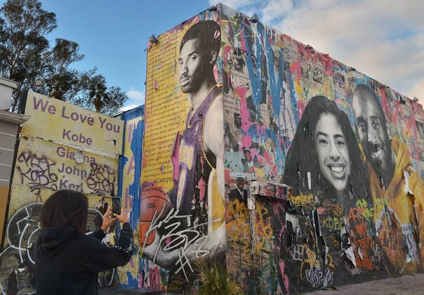 A visitor from Atlanta records a mural honoring Kobe Bryant and his daughter Gianna Bryant on Monday, January 25, 2021 in Los Angeles. One day ahead of the anniversary of the Calabasas helicopter crash that killed the Laker legend, his 13-year-old daughter and seven others, Sen. Dianne Feinstein (D-CA) and Rep. Brad Sherman (D-CA) announced a bill Tuesday that would require Terrain Avoidance Warning Systems on all helicopters carrying six or more passengers.  LAP2021012501 JIMxRUYMEN