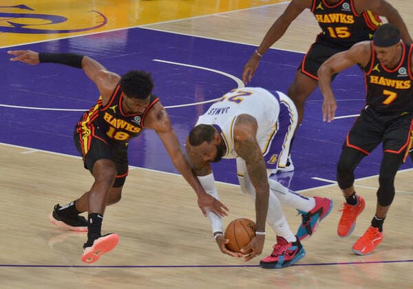 Los Angeles Lakers forward LeBron James and Atlanta Hawks forward Solomon Hill chase the loose ball before Hill slammed his body alongside James right leg for the foul during the first half at Staples Center in Los Angeles on Saturday, March 20, 2021. James reentered the game and drilled a three-pointer before asking to be taken out because of the pain to his right ankle. Without James, the Lakers lost to the Hawks 99-94.  LAP2021032003 JIMxRUYMEN