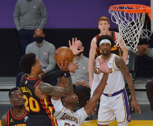 Atlanta Hawks forward John Collins scores over Los Angeles Lakers center Damian Jones during the first half at Staples Center in Los Angeles on Saturday, March 20, 2021. Le Bron James asked to be taken out of the game after suffering a right ankle injury. Without James, the Lakers lost to the Hawks 99-94.  LAP2021032010
