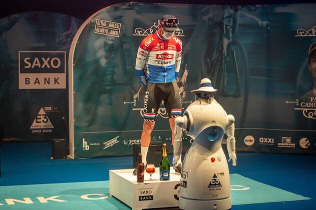 Radsport, E3 Harelbeke - Roboter führt Siegerehrung durch Dritter - Mathieu van der Poel (NED NL - Alpecin-Fenix) bei der Siegerehrung - hier bei der Siegerzeremonie mit eigenstaendiger Uebernahme der Medaille von einem ferngesteuerten Roboter der die Ehrendamen Podiumsdamen Hostessen wegen der Covid-19 Corona Pandemie und der angemahnten Kontaktbeschraenkungen ersetzt - hier abgeschottet in der Sporthalle von Harelbeke ohne Zuschauer wegen der Covid-19 Corona Pandemie - Podium - Siegerehrung - Ehrung - Auszeichnung - Zeremonie - Zelebrierung - Ceremony - Jubel - Freude - Luck - Emotion - Emotionen - Mimik - Mimic - Gestik - Gestic - Querformat quer horizontal Event Veranstaltung: 64. E3 Saxo Bank Classic - Harelbeke nach to Harelbeke 203.9 km - Ort Location: Harelbeke - Region: West-Vlaanderen (Flandern) - Land Country: Belgien Belgium - Datum Date: 26.03.2021