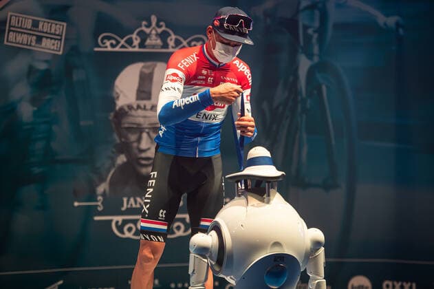 Radsport, E3 Harelbeke - Roboter führt Siegerehrung durch Dritter - Mathieu van der Poel (NED NL - Alpecin-Fenix) bei der Siegerehrung - hier bei der Siegerzeremonie mit eigenstaendiger Uebernahme der Medaille von einem ferngesteuerten Roboter der die Ehrendamen Podiumsdamen Hostessen wegen der Covid-19 Corona Pandemie und der angemahnten Kontaktbeschraenkungen ersetzt - hier abgeschottet in der Sporthalle von Harelbeke ohne Zuschauer wegen der Covid-19 Corona Pandemie - Podium - Siegerehrung - Ehrung - Auszeichnung - Zeremonie - Zelebrierung - Ceremony - Jubel - Freude - Luck - Emotion - Emotionen - Mimik - Mimic - Gestik - Gestic - Querformat quer horizontal Event Veranstaltung: 64. E3 Saxo Bank Classic - Harelbeke nach to Harelbeke 203.9 km - Ort Location: Harelbeke - Region: West-Vlaanderen (Flandern) - Land Country: Belgien Belgium - Datum Date: 26.03.2021