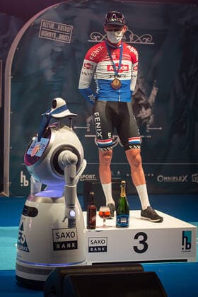 Radsport, E3 Harelbeke - Roboter führt Siegerehrung durch Dritter - Mathieu van der Poel (NED NL - Alpecin-Fenix) bei der Siegerehrung - hier bei der Siegerzeremonie mit eigenstaendiger Uebernahme der Medaille von einem ferngesteuerten Roboter der die Ehrendamen Podiumsdamen Hostessen wegen der Covid-19 Corona Pandemie und der angemahnten Kontaktbeschraenkungen ersetzt - hier abgeschottet in der Sporthalle von Harelbeke ohne Zuschauer wegen der Covid-19 Corona Pandemie - Podium - Siegerehrung - Ehrung - Auszeichnung - Zeremonie - Zelebrierung - Ceremony - Jubel - Freude - Luck - Emotion - Emotionen - Mimik - Mimic - Gestik - Gestic - Hochformat hoch hochkant vertikal Event Veranstaltung: 64. E3 Saxo Bank Classic - Harelbeke nach to Harelbeke 203.9 km - Ort Location: Harelbeke - Region: West-Vlaanderen (Flandern) - Land Country: Belgien Belgium - Datum Date: 26.03.2021
