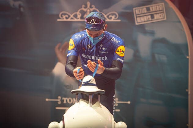 Radsport, E3 Harelbeke - Roboter führt Siegerehrung durch Zweiter - Florian Senechal (FRA - Deceuninck-Quick Step) bei der Siegerehrung - hier bei der Siegerzeremonie mit eigenstaendiger Uebernahme der Medaille von einem ferngesteuerten Roboter der die Ehrendamen Podiumsdamen Hostessen wegen der Covid-19 Corona Pandemie und der angemahnten Kontaktbeschraenkungen ersetzt - hier abgeschottet in der Sporthalle von Harelbeke ohne Zuschauer wegen der Covid-19 Corona Pandemie - Podium - Siegerehrung - Ehrung - Auszeichnung - Zeremonie - Zelebrierung - Ceremony - Jubel - Freude - Luck - Emotion - Emotionen - Mimik - Mimic - Gestik - Gestic - Querformat quer horizontal Event Veranstaltung: 64. E3 Saxo Bank Classic - Harelbeke nach to Harelbeke 203.9 km - Ort Location: Harelbeke - Region: West-Vlaanderen (Flandern) - Land Country: Belgien Belgium - Datum Date: 26.03.2021