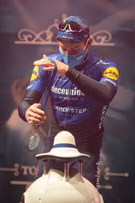 Radsport, E3 Harelbeke - Roboter führt Siegerehrung durch Zweiter - Florian Senechal (FRA - Deceuninck-Quick Step) bei der Siegerehrung - hier bei der Siegerzeremonie mit eigenstaendiger Uebernahme der Medaille von einem ferngesteuerten Roboter der die Ehrendamen Podiumsdamen Hostessen wegen der Covid-19 Corona Pandemie und der angemahnten Kontaktbeschraenkungen ersetzt - hier abgeschottet in der Sporthalle von Harelbeke ohne Zuschauer wegen der Covid-19 Corona Pandemie - Podium - Siegerehrung - Ehrung - Auszeichnung - Zeremonie - Zelebrierung - Ceremony - Jubel - Freude - Luck - Emotion - Emotionen - Mimik - Mimic - Gestik - Gestic - Hochformat hoch hochkant vertikal Event Veranstaltung: 64. E3 Saxo Bank Classic - Harelbeke nach to Harelbeke 203.9 km - Ort Location: Harelbeke - Region: West-Vlaanderen (Flandern) - Land Country: Belgien Belgium - Datum Date: 26.03.2021