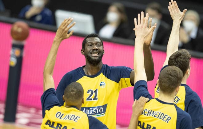 28.03.21, Berlin, Basketball, 1. Bundesliga, easyCredit BBL, Hauptrunde, 25.Spieltag, Mercedes Benz Arena: ALBA Berlin - Syntainics MBC. ALBAs Neuzugang Christ Koumadje (M) wird im Team begruesst von Louis Olinde (l) und Tim Schneider. ALBA Berlin - Syntainics MBC