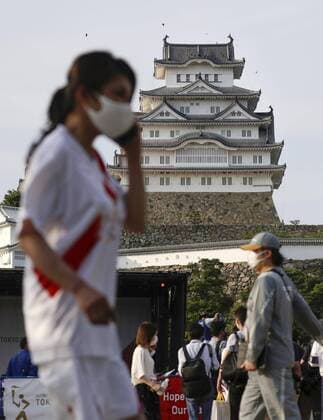 Tokyo Olympic torch relay event A Tokyo Olympic torch relay participant wearing a mask is pictured in front of Himeji Castle in Hyogo Prefecture on May 23, 2021, as an alternative event for the relay, in which participants pass the Olympic flame from torch to torch, is held. The torch relay was canceled in the western Japan prefecture with a coronavirus state of emergency remaining in place. 