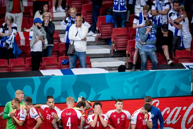 Danmarks Christian Eriksen faar behandling imens at danske spillere skaermer for ham og mens fans ser til i baggrunden under kampen mellem Danmark og Finland i gruppe B under EURO2020 i Parken i Koebenhavn, loerdag den 12. juni 2021.. , Copenhagen Denmark *** Denmarks Christian Eriksen receives treatment while Danish players screen for him and while fans watch in the background during the match between Denmark and Finland in group B during EURO2020 in the Park in Copenhagen, Saturday 12 June 2021, Copenhagen Denmark  Copyright: RitzauxScanpix MadsxClausxRasmussenx cop101 spdk20210612-200514-L