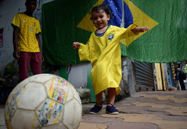 India: Brazil Football supporter support their team ahead of Copa America final in Kolkata A toddler wearing Brazil football jersey playing football next to a Brazil national flag ahead of Copa America Football final match between Brazil and Argentina in Kolkata. Kolkata West Bengal India Copyright: SudiptaxDas