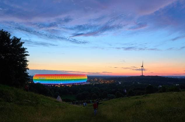 People on the Fröttmaninger Müllberg on the occasion of Christopher Street Day in Munich, the Allianz Arena is illuminated in rainbow colors, which symbolize the colors of the LBGTQ movement in Munich. Bavaria, Germany, July 10, 2021. LGBTQ stands for lesbian, gay, bisexual, transgender, and questioning (or queer).