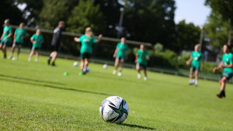 v.li.: Der Spielball liegt auf dem Spielfeld vor einer Trainingsgruppe, Symbolbild Training, Rasen, Gras, Boden, FLYERALARM Frauen-Bundesliga, adidas, Conext 21, Symbolfoto, Symbolbild Fussball, Fußball, Ball, Offizieller Ball, Offizieller Spielball, Offical Match Ball, Offical Matchball, 17.07.2021, Bremen (Deutschland), Fussball, Flyeralarm Frauen-Bundesliga, Trainingsauftakt SV Werder Bremen