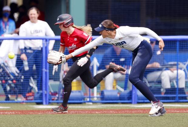 Tokyo Olympics: Softball U.S. pitcher Monica Abbott (R) tosses the ball with her glove as Emma Entzminger of Canada runs to first base in the fifth inning of their game in the opening round of the Tokyo Olympic softball tournament at Fukushima Azuma stadium in Fukushima, northeastern Japan, on July 22, 2021.  A14AA0000753445P