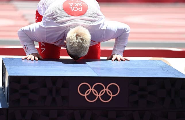 (210804) -- TOKYO, Aug. 4, 2021 -- Gold medalist Anita Wlodarczyk of Poland kisses the podium on the awarding ceremony of the women s hammer throw at the Tokyo 2020 Olympic Games, Olympische Spiele, Olympia, OS in Tokyo, Japan, Aug. 4, 2021. ) (TOKYO2020)XHTP-JAPAN-TOKYO-OLY-ATHLETICS-WOMEN S HAMMER THROW-AWARDING CEREMONY LixYibo 