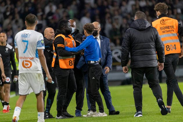 A steward (C) restrains a pitch invader (R) in front of Marseille s Argentine head coach Jorge Sampaoli (REAR) after the French L1 football match between Angers SCO and Marseille, at the Raymond-Kopa Stadium, in Angers, western France, on September 22, 2021  Copyright: xJeremiasxGonzalezx