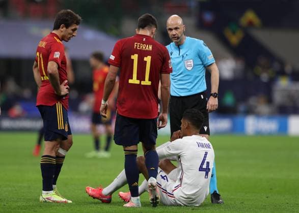 Milan, Italy, 10th October 2021. The referee Michael Oliver of England and Mikel Oyarzabal and Ferran Torres of Spain look on as Raphael Varane of France waits for treatment before being substituted during the UEFA Nations League match at Stadio Giuseppe Meazza, Milan. Picture credit should read: Jonathan Moscrop Sportimage EDITORIAL USE ONLY. No use with unauthorised audio, video, data, fixture lists, club league logos or live services. Online in-match use limited to 120 images, no video emulation. No use in betting, games or single club league player publications. SPI-1236-0011