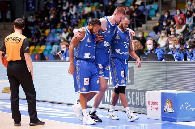 Fraport Skyliners - Syntainics MBC, easyCredit-BBL Quantez Robertson (Fraport Skyliners, 23) und Rasheed Moore (Fraport Skyliners, 20) führen den verletzten Matt Haarms (Fraport Skyliners, 3) vom Platz. Basketball-Spiel des easyCredit BBL zwischen den Fraport Skyliners und dem Mitteldeutschen Basketball Club am 19. Dezember 2021 in der Ballsporthalle in Frankfurt am Main., Frankfurt am Main Hessen Deutschland Ballsporthalle