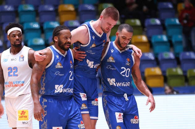 Fraport Skyliners - Syntainics MBC, easyCredit-BBL Quantez Robertson (Fraport Skyliners, 23) und Rasheed Moore (Fraport Skyliners, 20) führen den verletzten Matt Haarms (Fraport Skyliners, 3) vom Platz. Links Chris Coffey (Mitteldeutscher BC, 22). Basketball-Spiel des easyCredit BBL zwischen den Fraport Skyliners und dem Mitteldeutschen Basketball Club am 19. Dezember 2021 in der Ballsporthalle in Frankfurt am Main., Frankfurt am Main Hessen Deutschland Ballsporthalle