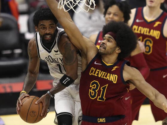 Brooklyn Nets Kyrie Irving (11) makes a pass around Cleveland Cavaliers Jarrett Allen (31) at Rocket Mortgage Field House in Cleveland, Ohio on Monday, January 17, 2022.  CLE20220117109 AARONxJOSEFCZYK