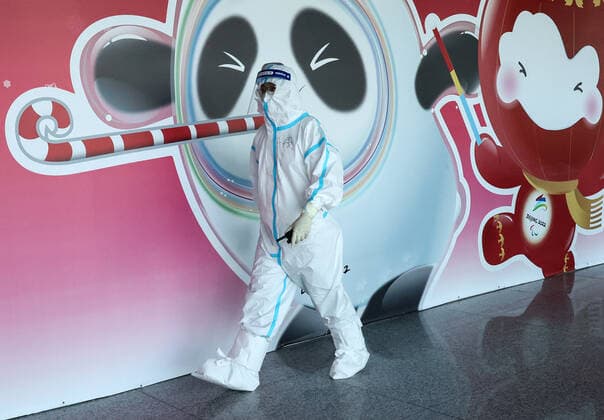 BEIJING, CHINA - JANUARY 28, 2022: An employee is seen by a poster depicting Bing Dwen Dwen (L), the mascot of the 2022 Winter Olympics, and Shuey Rhon Rhon, the mascot of the 2022 Winter Paralympics, at Beijing Capital International Airport. The 24th Winter Olympic Games, Olympische Spiele, Olympia, OS are scheduled to take place in Beijing on February 4-20, 2022. Valery Sharifulin TASS 0149073047st