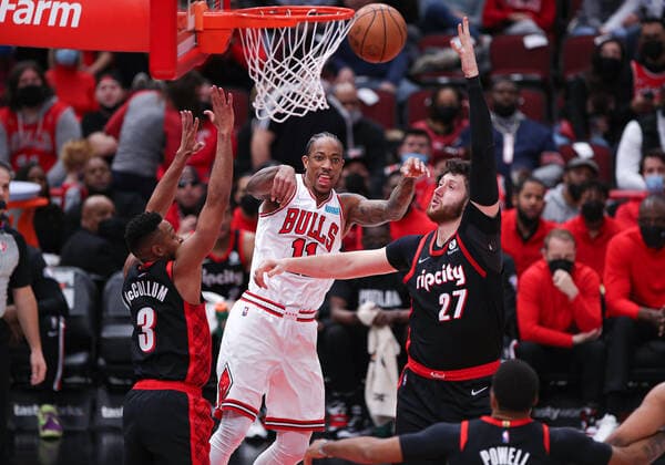 CHICAGO, IL - JANUARY 30: Chicago Bulls forward DeMar DeRozan (11) passes the ball between Portland Trail Blazers guard CJ McCollum (3) and Portland Trail Blazers center Jusuf Nurkic (27) during a NBA, Basketball Herren, USA game between the Portland Trail Blazers and the Chicago Bulls on January 30, 2022 at the United Center in Chicago, IL. (Photo by Melissa Tamez Icon Sportswire) NBA: JAN 30 Trail Blazers at Bulls Icon22013062