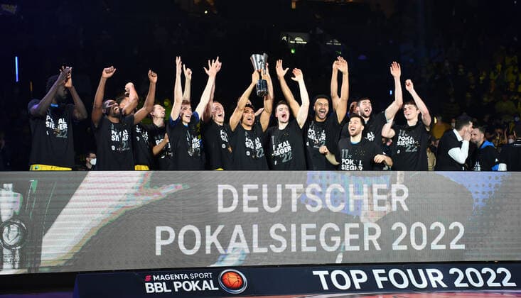 Basketball, Herren, Saison 2021 2022, MagentaSport BBL Pokal, Top Four (Finale), Hakro Merlins Crailsheim - Alba Berlin, Maodo Lo (Alba Berlin) streckt den Pokal in die Luft, 20.02. 2022, Copyright: xSebastianxRäppold MatthiasxKochx