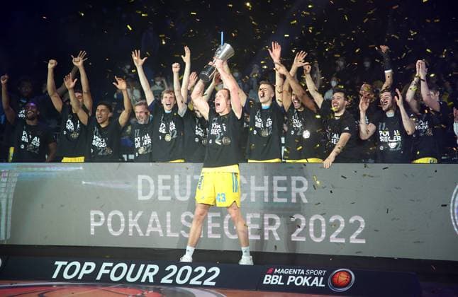 Pokalsieger Luke Sikma mit dem Pokal dahinter die Mannschaft Freude Emotion Jubel nach Spielende Mannschaftsfoto Basketball BBL Pokal Top Four Herren Finale Saison 2021 2022 20.02.2022 Alba Berlin vs. HAKRO Merlins Crailsheim
