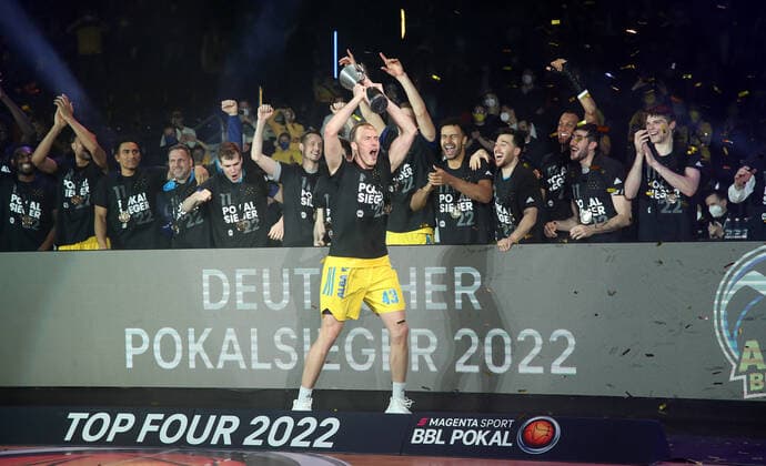 Pokalsieger Luke Sikma mit dem Pokal dahinter die Mannschaft Freude Emotion Jubel nach Spielende Mannschaftsfoto Basketball BBL Pokal Top Four Herren Finale Saison 2021 2022 20.02.2022 Alba Berlin vs. HAKRO Merlins Crailsheim