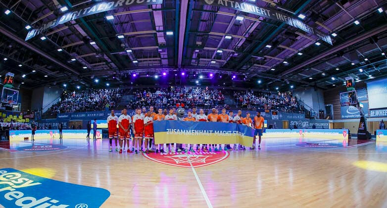 04.03.2022, Basketball, BBL, Hauptrunde, s.Oliver Wuerzburg - ratiopharm ulm, GER, Wuerzburg, tectake Arena Bild: v. li. Die Spieler von Ulm und Wuerzburg zeigen durch einen Banner Solidaritaet mit der Ukraine. Copyright: HMBxMedia xHeikoxBecker