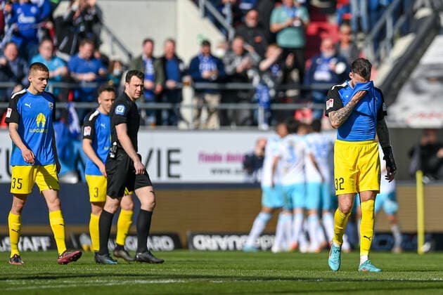 Spieler des FC Ingolstadt nach dem Gegentor zum 0:1 enttäuscht schauend, Enttäuschung, Frustration, disappointed, pessimistisch, im Hintergrund bejubeln die Schalker Spieler das Tor, 13.03.2022, Ingolstadt (Deutschland), Fussball, 2. Bundesliga, FC Ingolstadt 04 - FC Schalke 04, DFB DFL REGULATIONS PROHIBIT ANY USE OF PHOTOGRAPHS AS IMAGE SEQUENCES AND OR QUASI-VIDEO.