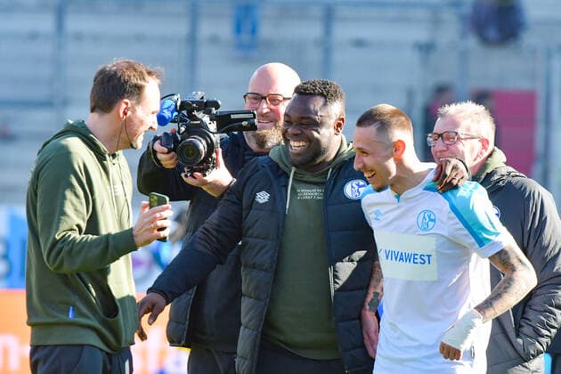 Schalker Urgestein Gerald Asamoha informiert hier den wegen Corona nicht anwesenden Cheftrainer Michael Bueskens (Schalke 04) mit Darko Churlinov (Schalke 04, Nr.7) ueber den Sieg beim Spiel FC Ingolstadt 04 gegen Schalke 04 am 13.03.2022, DFL regulations prohibit any use of photographs as image sequences and or quasi-video. GER, Fussball, 2. Bundesliga, Spieltag 26, FC Ingolstadt 04 gegen Schalke 04, 13.03.2022, Audi Sportpark Ingolstadt