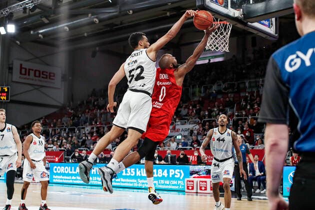 links Trent Lockett (Niners Chemnitz, 52) blockt rechts Chris Dowe (Brose Bamberg, 00) beim Korbleger Brose Bamberg - Niners Chemnitz - easyCredit-BBL - Basketball Bundesliga Saison 2021 22 Spieltag 29, 08.04.2022 Bamberg, Brose Arena Foto: Daniel Löb Loeb Copyright: DanielxLöb