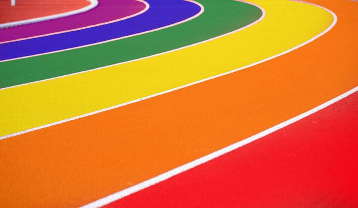 Symbolbild Queer im Laufbahn einer Leichtathletikanlage in Regenbogenfarben (Composing)