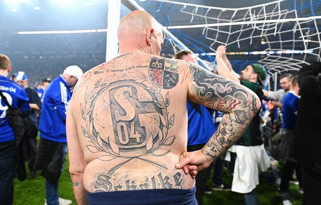 Fussball, 2. Bundesliga, Deutschland, Herren, Saison 2021 2022, 1. Spieltag, VELTINS Arena Gelsenkirchen: FC Schalke 04 (blau) - FC St. Pauli (weiss) 3:2; Ein Schalke Fan mit riesigem S04 Tattoo auf dem Rücken. Fan, Fans, Fankultur, Begeisterung, Tattoo, Jubel, Freude, Aktion. DFB DFL REGULATIONS PROHIBIT ANY USE OF PHOTOGRAPHS AS IMAGE SEQUENCES AND OR QUASI-VIDEO