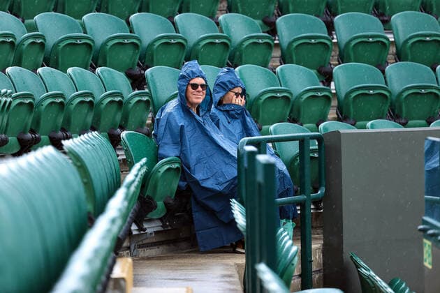 Tennis - Wimbledon (Day 1) 27th June 2022 - Tennis - Wimbledon (Day 1) - Two spectators sit in raincoats, waiting for play to resume - Photo: Simon Stacpoole Offside. London UK Copyright: xSimonxStacpoolexOffside