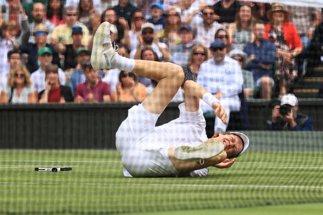 Tennis - Wimbledon (Day 9) 5th July 2022 - Tennis - Wimbledon (Day 9) - Jannik Sinner (ITA) grimaces in pain as he rolls his ankle and slips during his Gentlemen s Singles Quarter Final match against Novak Djokovic (SRB) - Photo: Simon Stacpoole Offside. London UK Copyright: xSimonxStacpoolexOffside