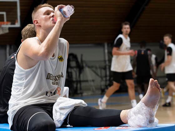 Basketball: Medientraining der Herren-Nationalmannschaft am 08.08.2022 in Köln (Nordrhein-Westfalen). Robin Benzing trinkt aus einer Flasche und kühlt seinen linken Knöchel Copyright: xKirchner MarcoxSteinbrennerx