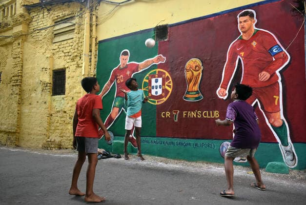 India: Daily life during FIFA World Cup, WM, Weltmeisterschaft, Fussball 2022 in Kolkata Children are playing in front of the wall art of Portugal s soccer Cristiano Ronaldo and João Cancelo along a road during the FIFA World cup 2022 in Kolkata. Kolkata West Bengal India Copyright: SudiptaxDas