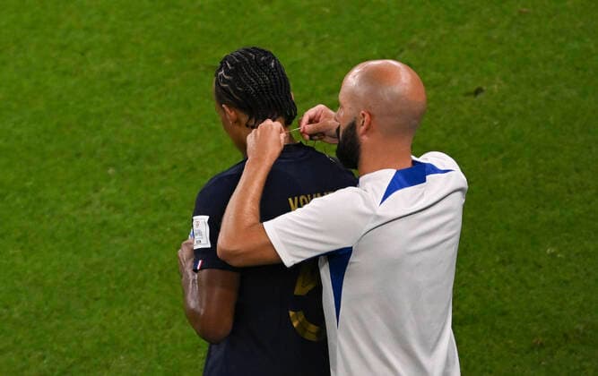 (221204) -- DOHA, Dec. 4, 2022 -- Jules Kounde (L) of France has his necklace taken off during the Round of 16 match between France and Poland of the 2022 FIFA World Cup, WM, Weltmeisterschaft, Fussball at Al Thumama Stadium in Doha, Qatar, Dec. 4, 2022. ) (SP)QATAR-DOHA-2022 WORLD CUP-ROUND OF 16-FRA VS POL XiaxYifang 